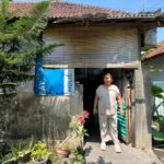 Widiani steht vor ihrem Wäscheservice in Denpasar, Bali, neben Wäsche und Pflanzen.