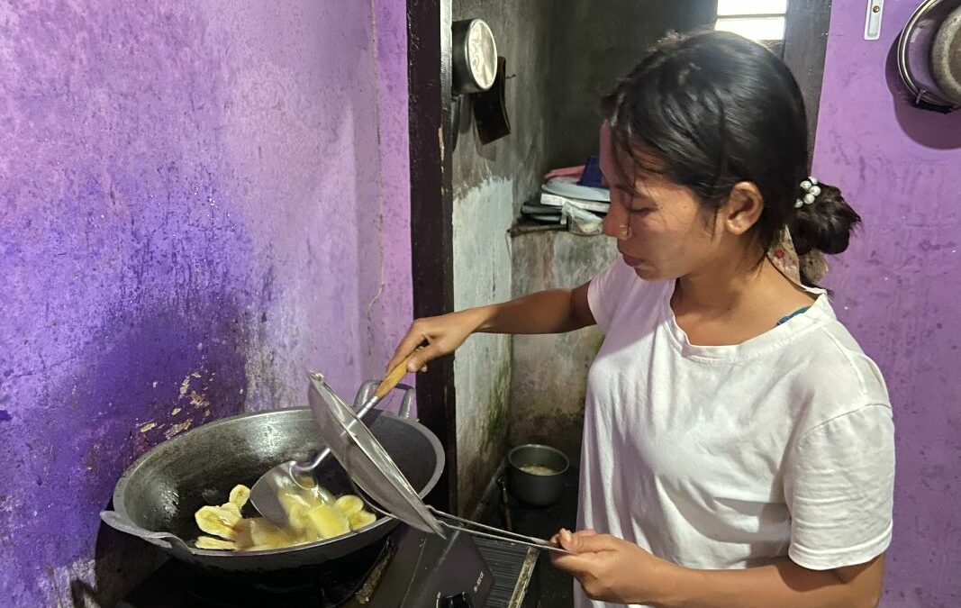 Erna frittiert Bananenchips in einem Wok auf ihrem kleinen Gaskocher.