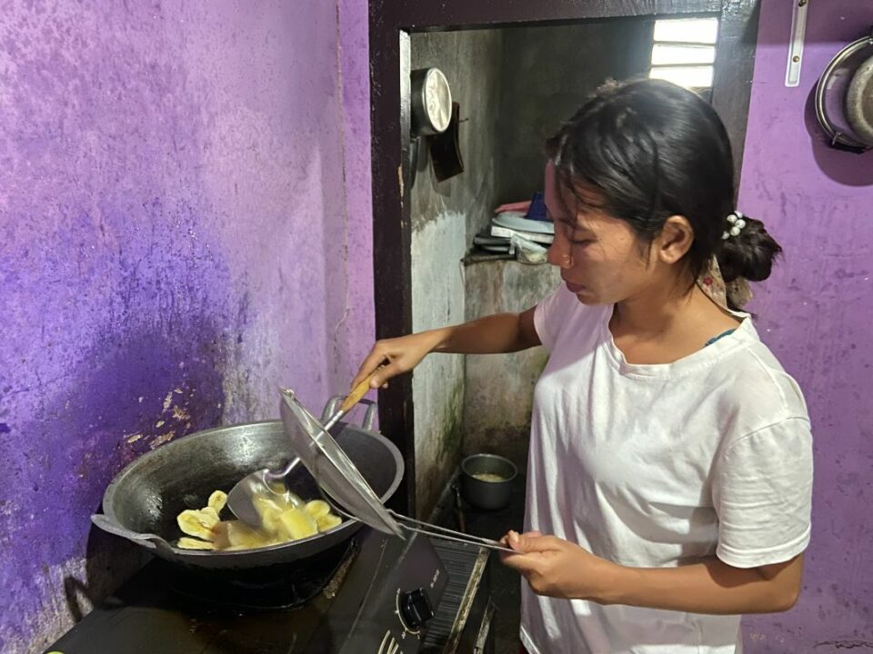 Erna frittiert Bananenchips in einem Wok auf ihrem kleinen Gaskocher.