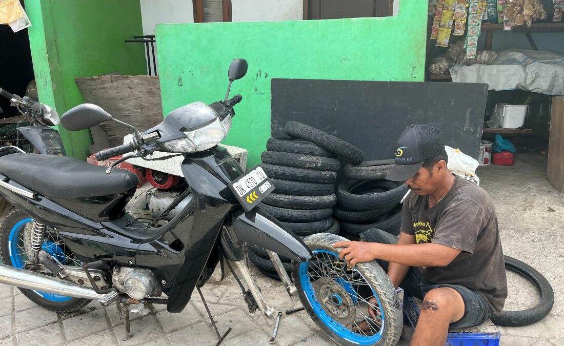 Ein Mann sitzt am Boden und repariert ein Motorrad