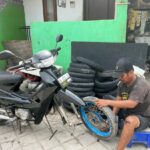 Ein Mann sitzt am Boden und repariert ein Motorrad