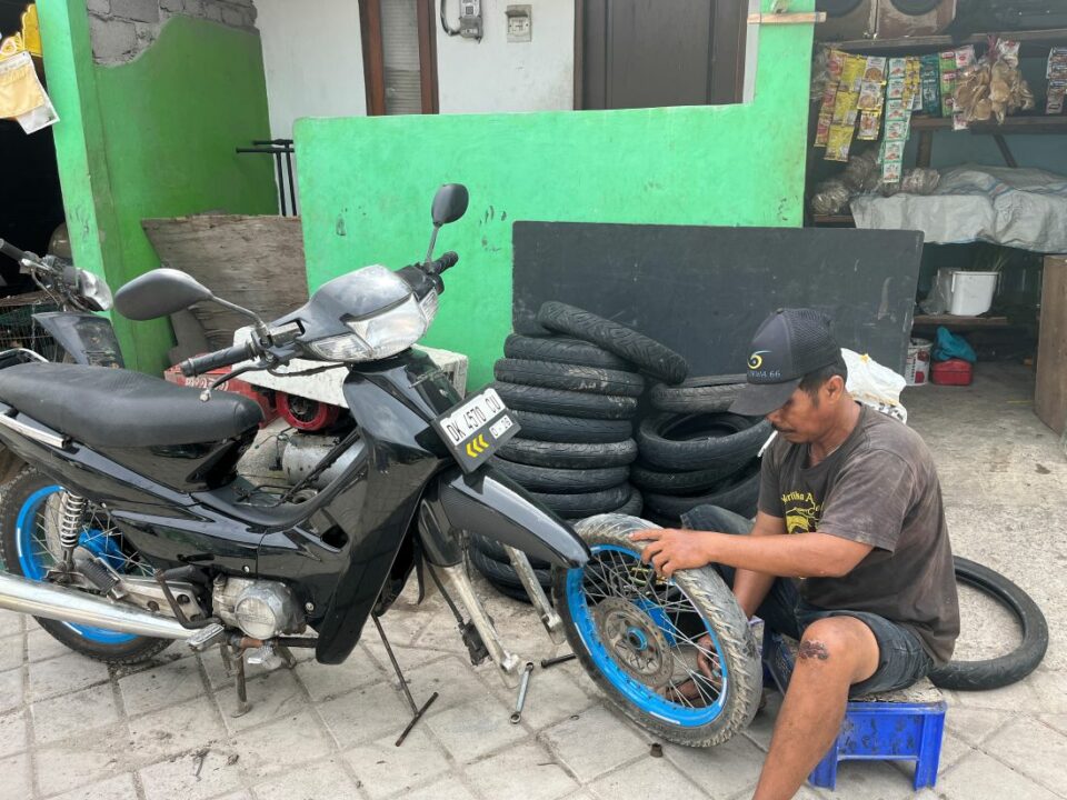 Ein Mann sitzt am Boden und repariert ein Motorrad