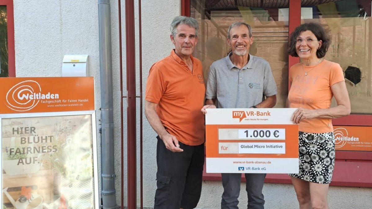 Vorstandsmitglied Achim steht zwischen zwei Personen aus dem Weltladen Karlstein e. V., die einen Spendenscheck halten.