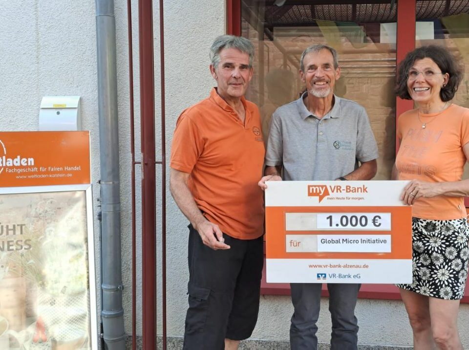 Vorstandsmitglied Achim steht zwischen zwei Personen aus dem Weltladen Karlstein e. V., die einen Spendenscheck halten.