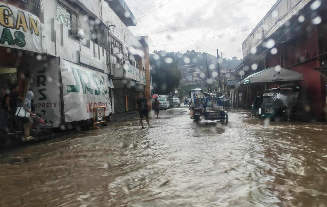 Überflutete Straße in Olongapo auf den Philippinen: Menschen und ein Tricycle bewegen sich im August 2026 durch das Hochwasser