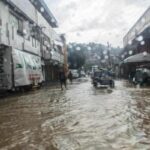 Überflutete Straße in Olongapo auf den Philippinen: Menschen und ein Tricycle bewegen sich im August 2026 durch das Hochwasser