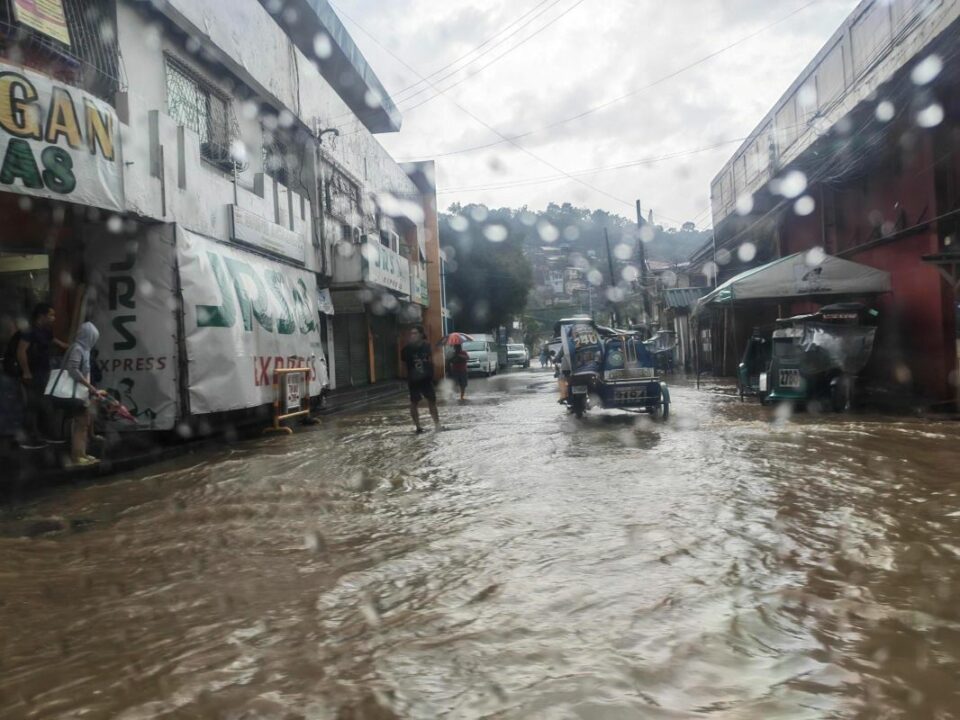 Überflutete Straße in Olongapo auf den Philippinen: Menschen und ein Tricycle bewegen sich im August 2026 durch das Hochwasser